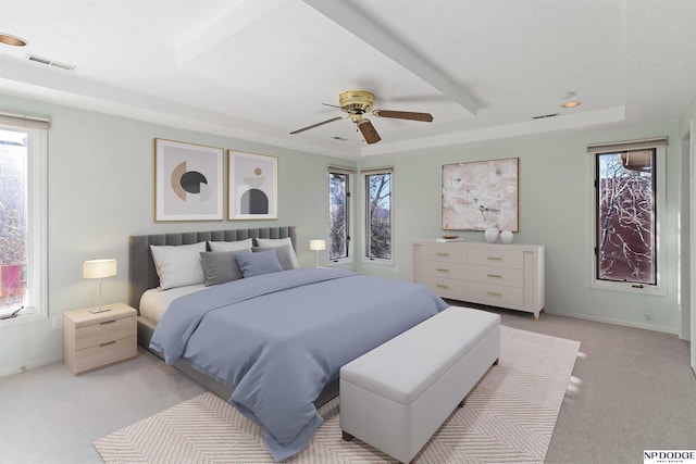 carpeted bedroom with a raised ceiling and ceiling fan