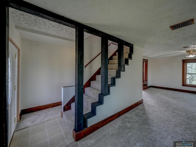 staircase featuring carpet flooring, a textured ceiling, and ceiling fan