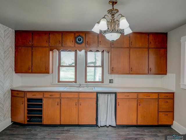 kitchen with dark wood-type flooring, an inviting chandelier, dishwasher, and sink