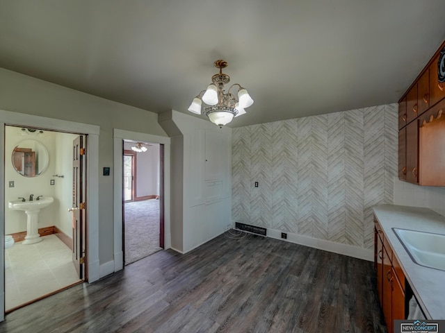 unfurnished dining area featuring sink, dark wood-type flooring, and a chandelier