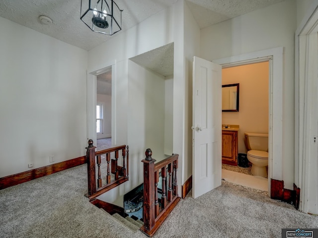 corridor featuring a textured ceiling and light carpet