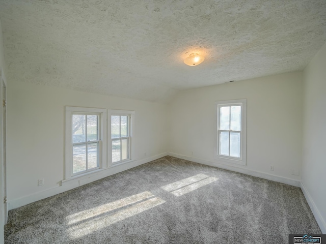 carpeted empty room featuring a textured ceiling and vaulted ceiling