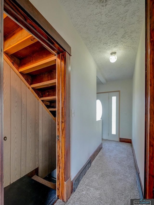 corridor with a textured ceiling, wood walls, and carpet flooring