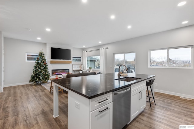 kitchen with sink, white cabinets, dishwasher, an island with sink, and a breakfast bar area