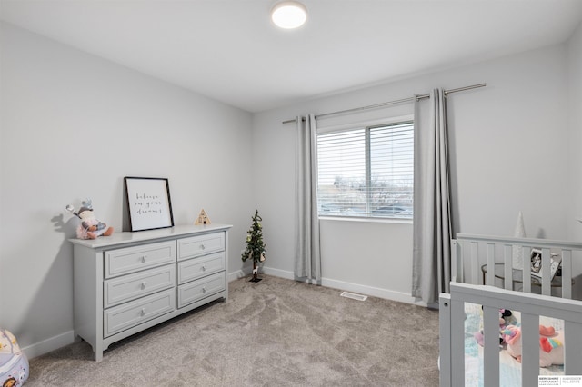 bedroom featuring a nursery area and light carpet