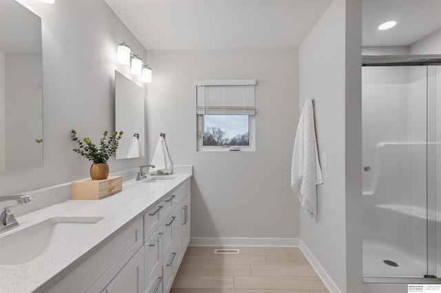 bathroom featuring a shower with door and vanity