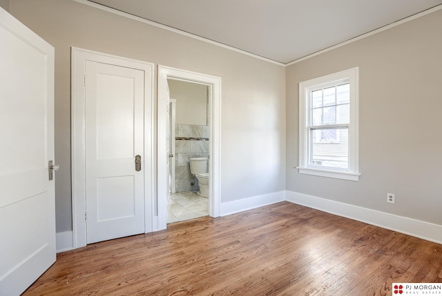 unfurnished bedroom with crown molding, hardwood / wood-style floors, and ensuite bath