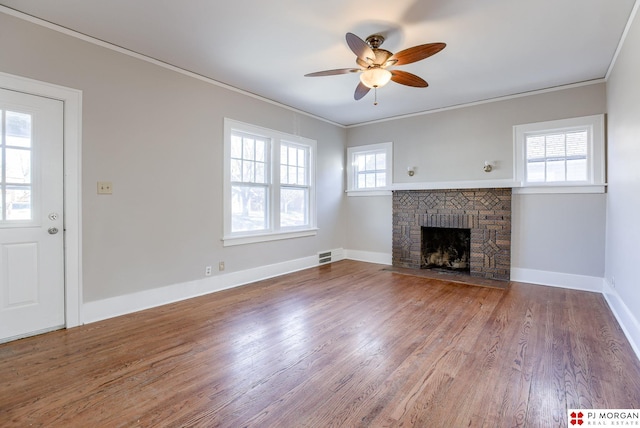 unfurnished living room featuring wood-type flooring, a fireplace, ornamental molding, and a healthy amount of sunlight