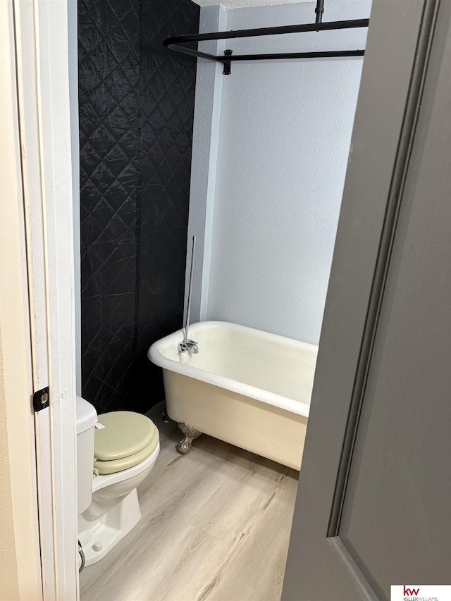 bathroom with toilet, wood-type flooring, and a tub