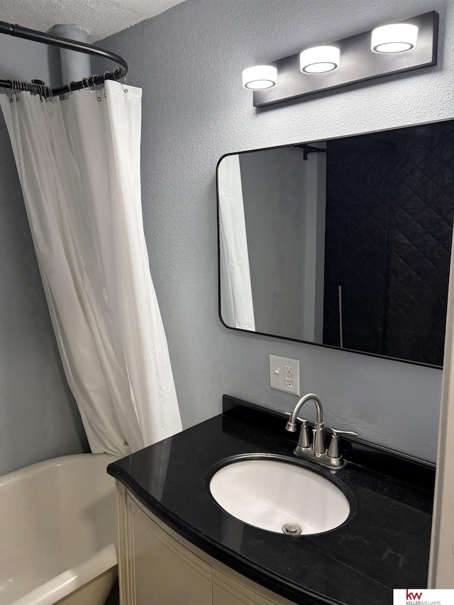 bathroom with a textured ceiling, shower / tub combo, and vanity