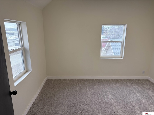 spare room with carpet flooring and vaulted ceiling