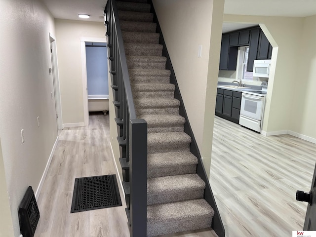 stairway with sink and hardwood / wood-style flooring