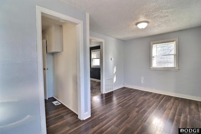 empty room featuring a textured ceiling and dark hardwood / wood-style floors