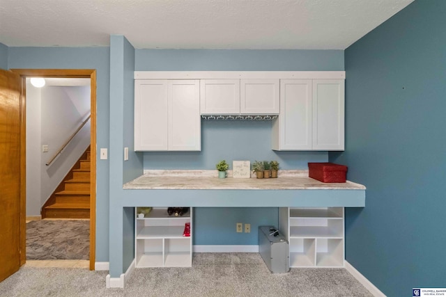 kitchen featuring white cabinetry, a textured ceiling, and light colored carpet