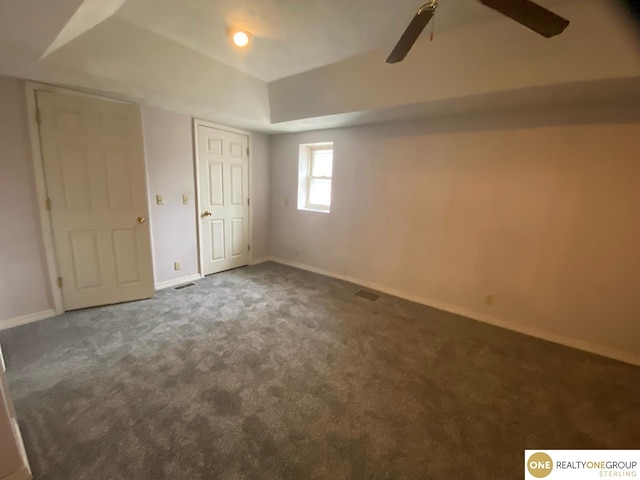 basement with ceiling fan and dark colored carpet