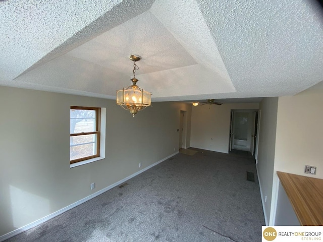 carpeted empty room featuring ceiling fan with notable chandelier, a textured ceiling, and a tray ceiling