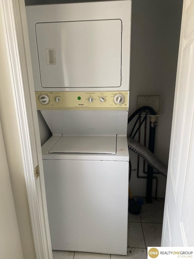 laundry room featuring stacked washing maching and dryer and light tile patterned flooring