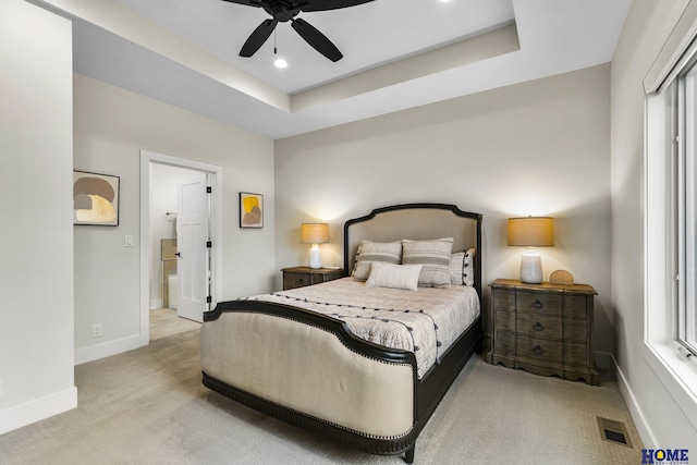 carpeted bedroom with ceiling fan and a tray ceiling