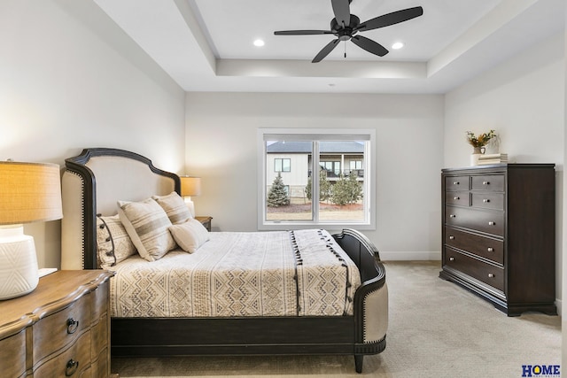 bedroom featuring a raised ceiling, ceiling fan, and light carpet