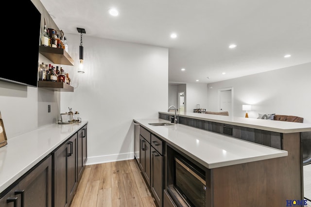 kitchen featuring sink, decorative light fixtures, a kitchen bar, light hardwood / wood-style floors, and kitchen peninsula