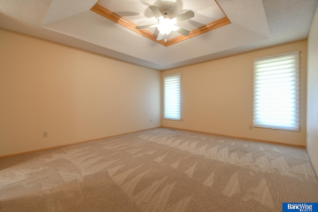 carpeted spare room with ceiling fan, crown molding, and a raised ceiling