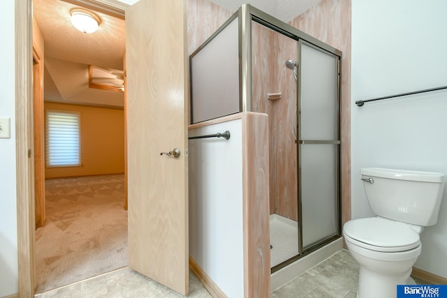 bathroom featuring toilet, a textured ceiling, and a shower with shower door