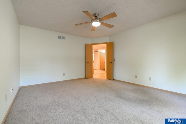 carpeted empty room featuring ceiling fan and a textured ceiling