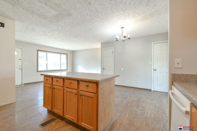 kitchen featuring decorative light fixtures, an inviting chandelier, a center island, dishwasher, and light hardwood / wood-style flooring