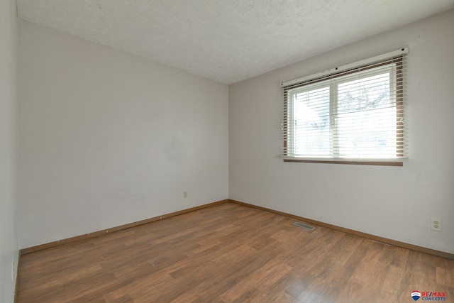 unfurnished room with a textured ceiling and hardwood / wood-style flooring