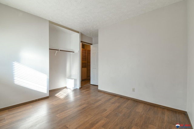 unfurnished bedroom featuring dark hardwood / wood-style flooring, a closet, and a textured ceiling