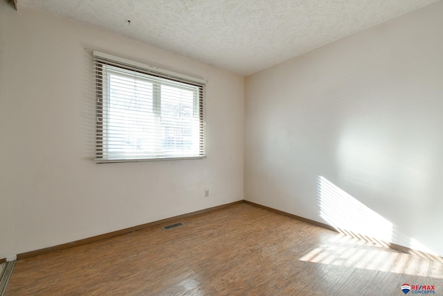 unfurnished room with a textured ceiling and wood-type flooring