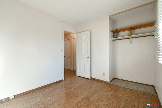 unfurnished bedroom with a textured ceiling, hardwood / wood-style floors, and a closet