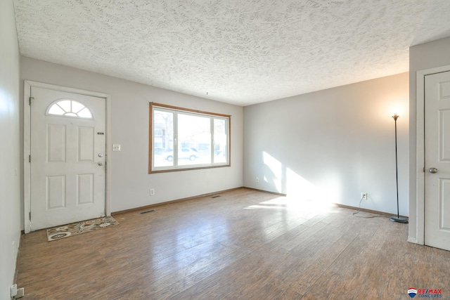 foyer with a healthy amount of sunlight, a textured ceiling, and wood-type flooring