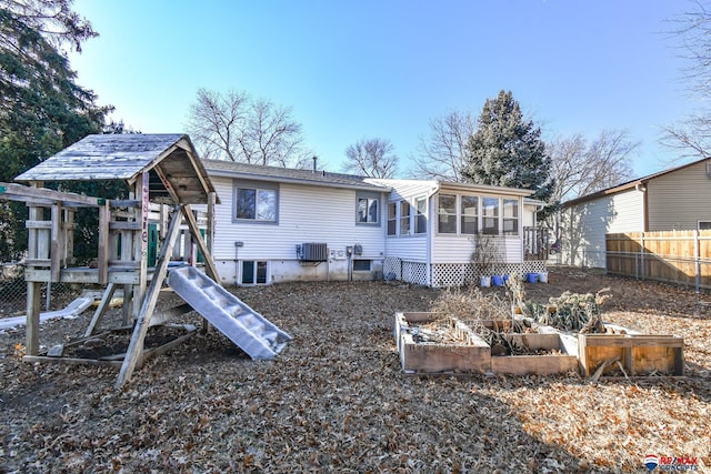 rear view of house with a playground, cooling unit, and a sunroom