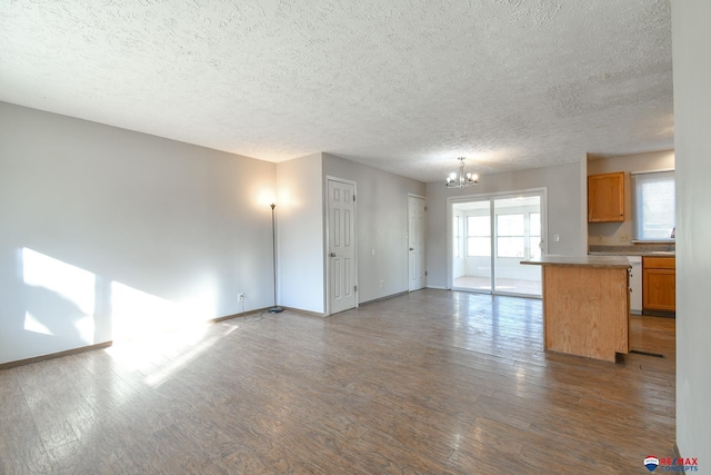 unfurnished living room with a textured ceiling, an inviting chandelier, and hardwood / wood-style flooring