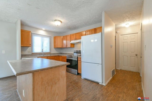 kitchen featuring white fridge, wood-type flooring, stainless steel range with electric stovetop, a kitchen island, and sink