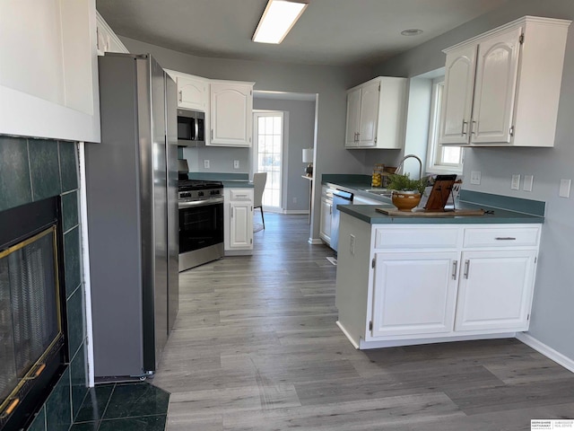 kitchen featuring white cabinetry, stainless steel appliances, a fireplace, and sink