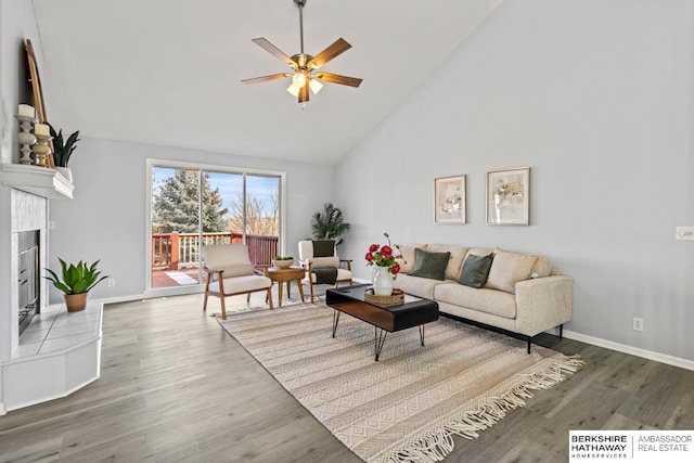 living room featuring hardwood / wood-style flooring, ceiling fan, high vaulted ceiling, and a fireplace