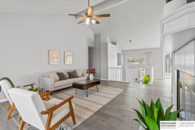 living room with beamed ceiling, wood-type flooring, a fireplace, and high vaulted ceiling