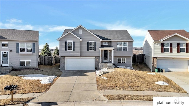 bi-level home featuring concrete driveway, an attached garage, and fence