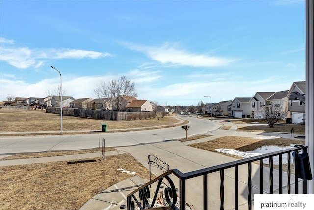 view of road featuring sidewalks, curbs, a residential view, and street lighting