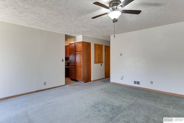 carpeted spare room with ceiling fan and a textured ceiling