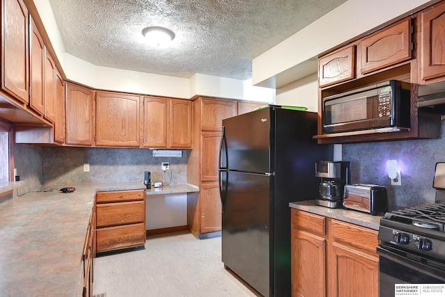 kitchen featuring black appliances, ventilation hood, backsplash, and a textured ceiling