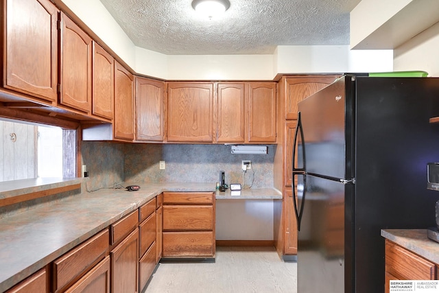 kitchen with black fridge, a textured ceiling, and backsplash