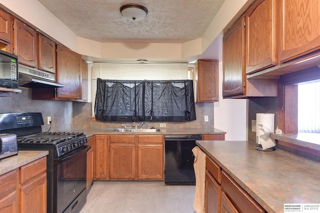 kitchen featuring light wood-type flooring, black appliances, a textured ceiling, and sink