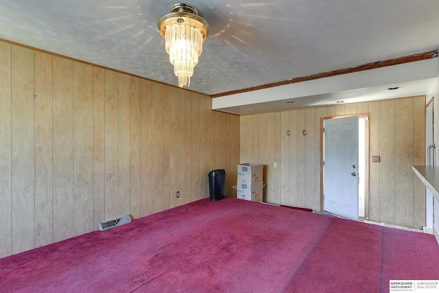 unfurnished room featuring a textured ceiling, wood walls, and crown molding