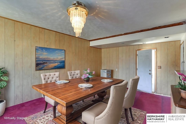 dining room featuring a textured ceiling, a chandelier, crown molding, and wood walls