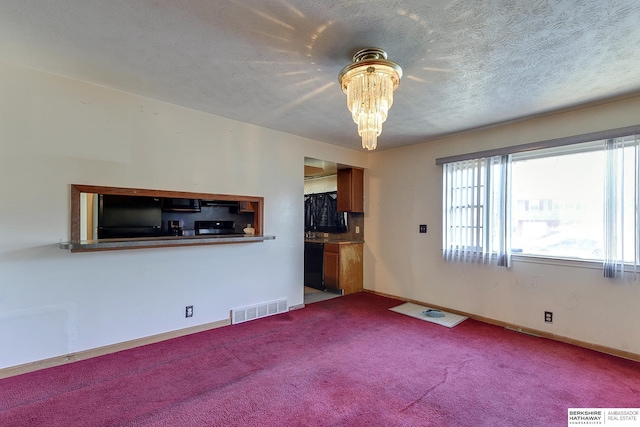 unfurnished living room with carpet flooring, a textured ceiling, and an inviting chandelier