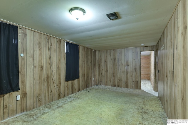 empty room with carpet floors and wood walls