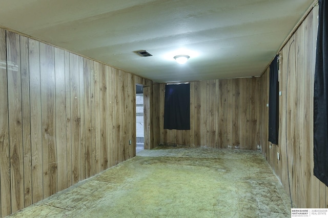 carpeted empty room with wood walls